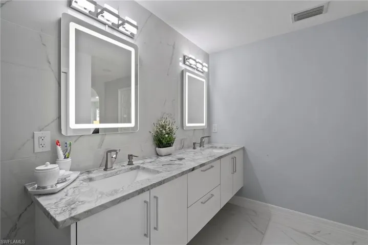 Bathroom with double vanity and marble finish floors