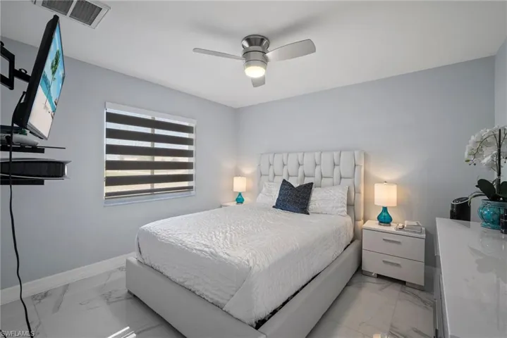 Bedroom featuring light marble finish floors and ceiling fan