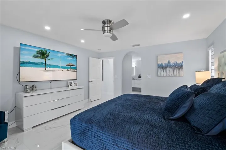 Bedroom featuring light marble finish floors, arched walkways, recessed lighting, and ceiling fan