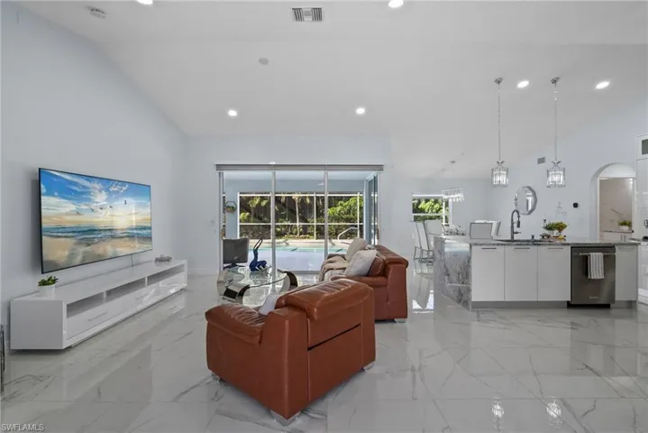 Living room with light marble finish flooring, recessed lighting, arched walkways, and high vaulted ceiling