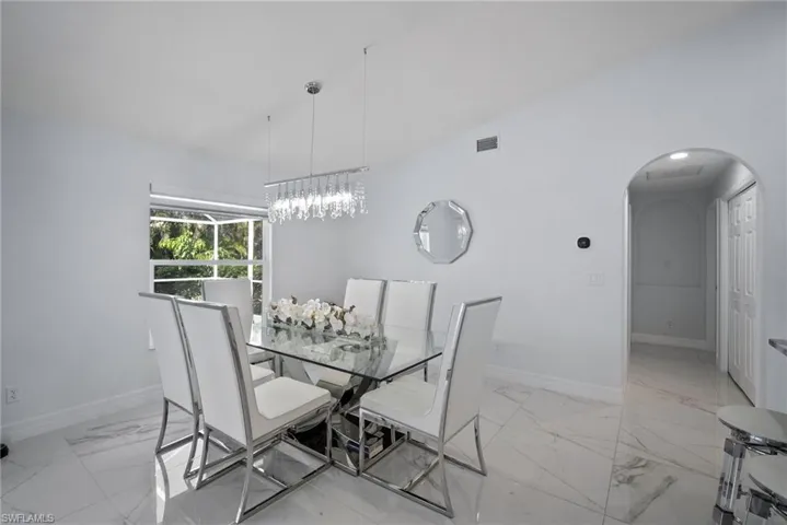 Dining area featuring light marble finish flooring, arched walkways, and a chandelier