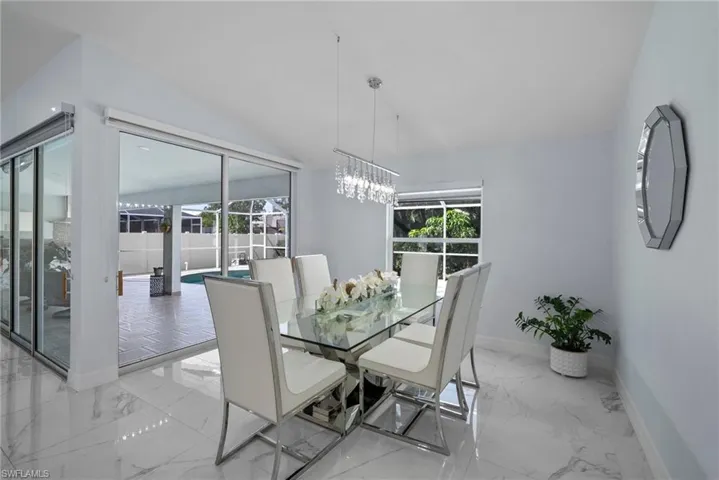 Dining room featuring light marble finish floors, a chandelier, and lofted ceiling