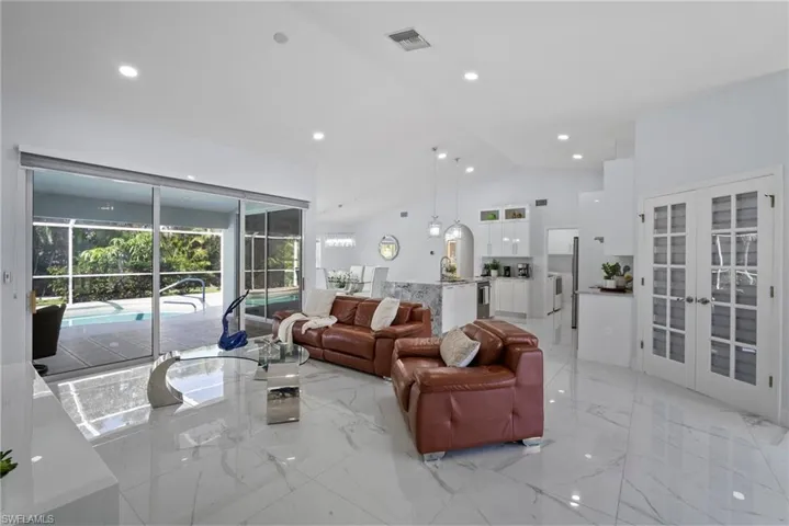 Living room featuring french doors, light marble finish floors, high vaulted ceiling, and recessed lighting
