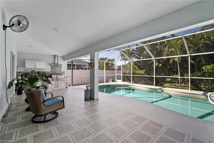 Outdoor pool featuring a patio, glass enclosure, and area for grilling