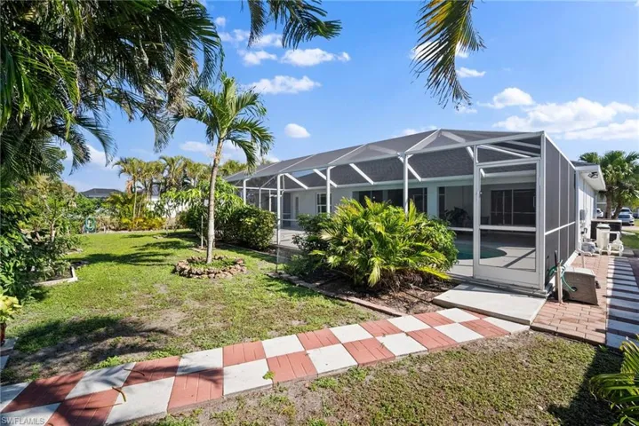 View of grassy yard featuring a patio area and glass enclosure