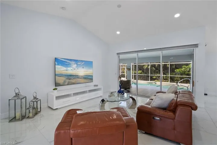 Living room featuring light marble finish flooring, lofted ceiling, recessed lighting, and a sunroom