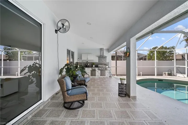 View of pool with an outdoor kitchen, a patio, and glass enclosure