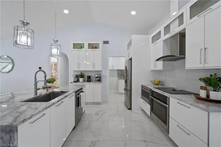 Kitchen with stainless steel appliances, extractor fan, modern cabinets, decorative light fixtures, and decorative backsplash