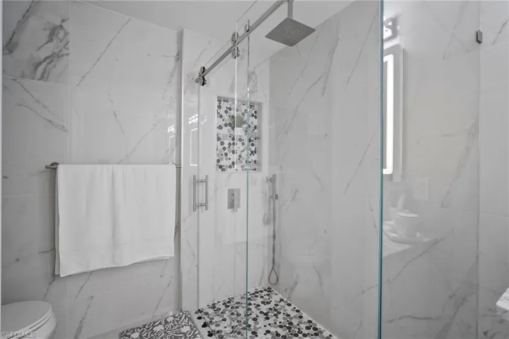 Bathroom with toilet and a marble finish shower