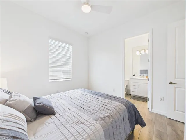 Bedroom featuring light wood-type flooring, a ceiling fan, and ensuite bathroom