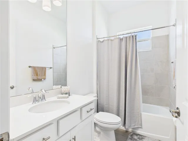 Full bath featuring shower / bath combination with curtain, vanity, and dark wood-type flooring