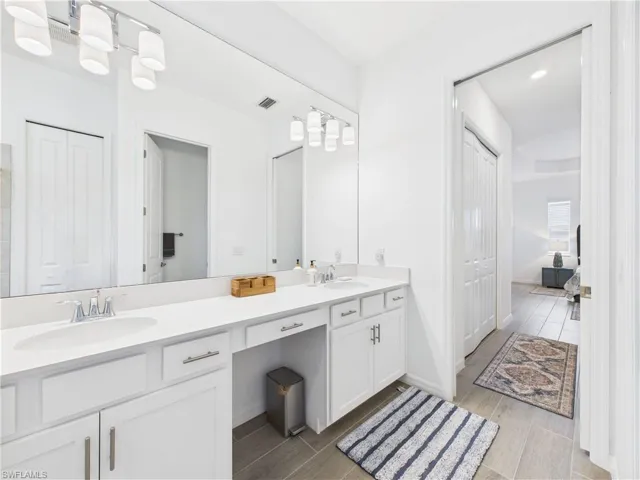 Full bath with wood finish floors, double vanity, and a closet