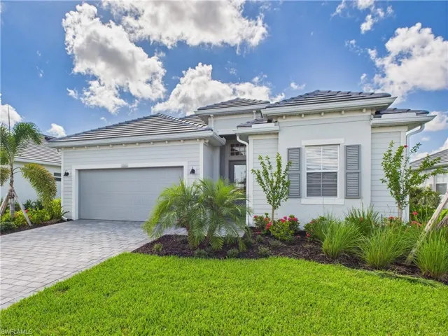 Prairie-style home featuring a garage, decorative driveway, a front yard, and stucco siding