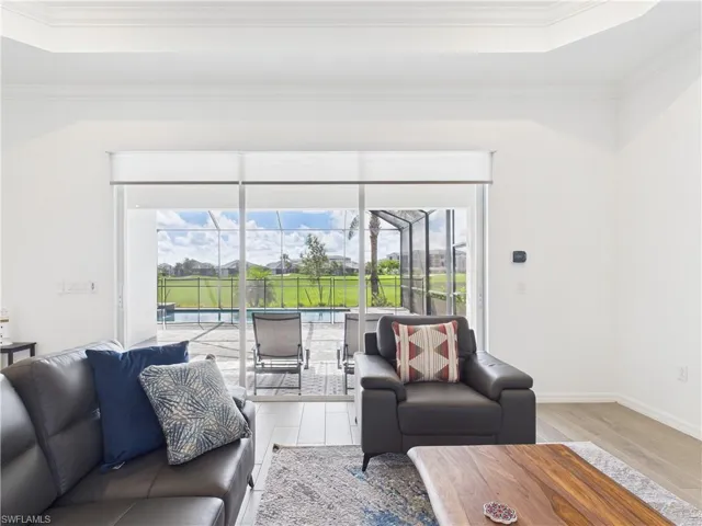 Living area featuring ornamental molding, a tray ceiling, light wood finished floors, and a sunroom