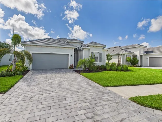 View of front facade featuring decorative driveway, a garage, a front yard, and a tile roof