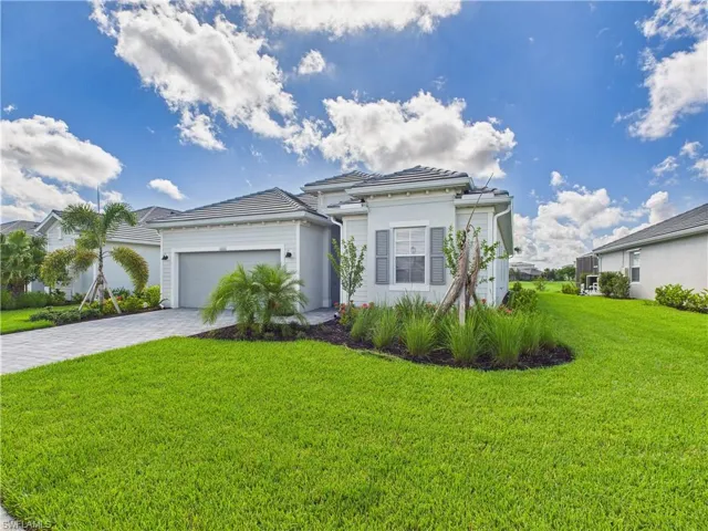 View of front of property with an attached garage, a front lawn, and decorative driveway
