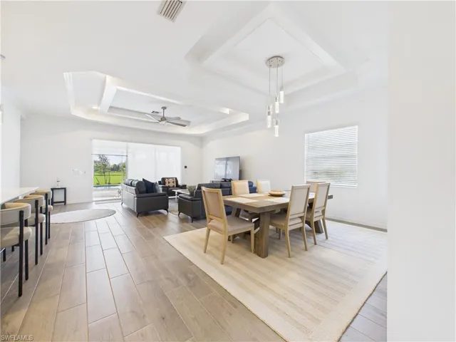 Dining room featuring a tray ceiling, a ceiling fan, and light wood-style floors