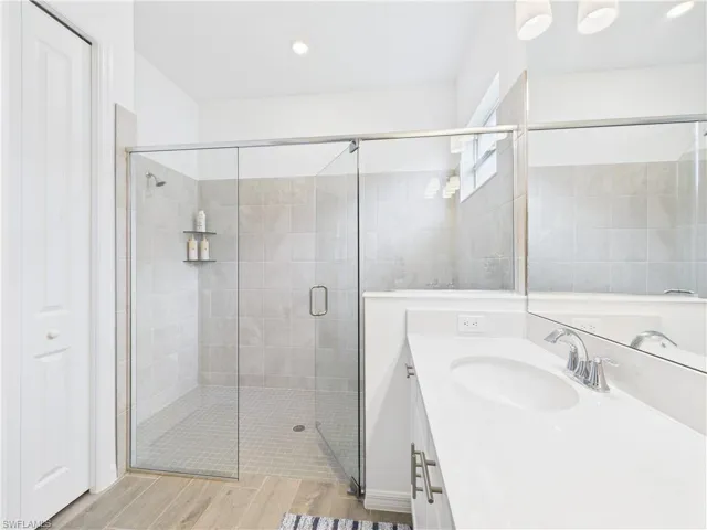 Bathroom featuring vanity, a stall shower, wood tiled floors, and recessed lighting