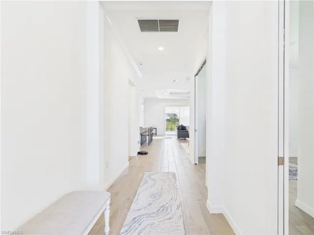 Corridor with light wood-style flooring and recessed lighting