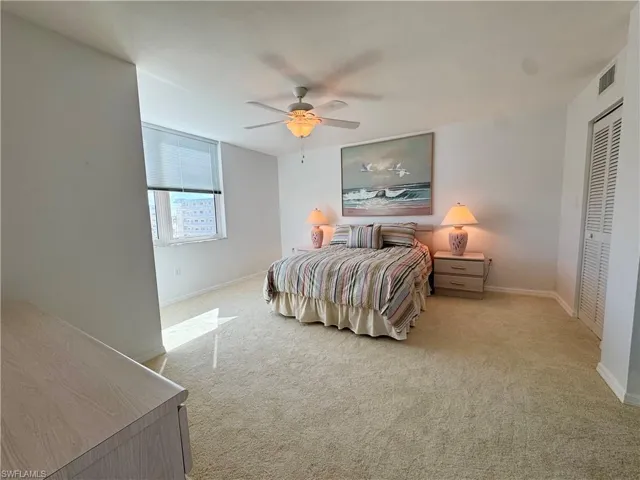Bedroom with light carpet, a ceiling fan, and a closet