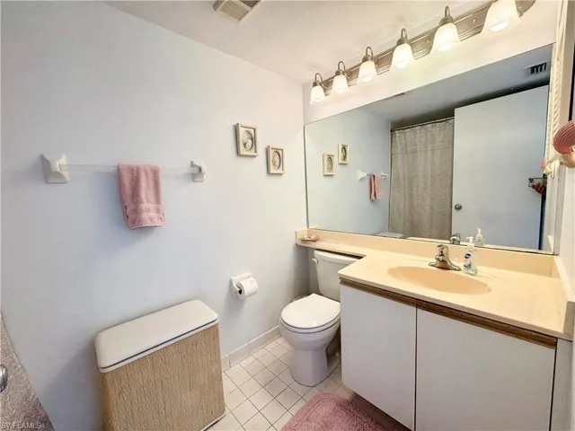 Bathroom with curtained shower, vanity, and light tile patterned flooring