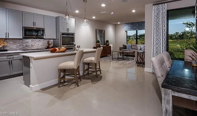 Kitchen with gray cabinets, tasteful backsplash, pendant lighting, a kitchen bar, and recessed lighting