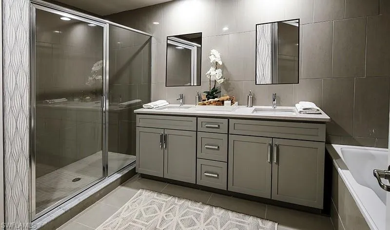 Bathroom featuring double vanity, a shower stall, light tile patterned floors, tile walls, and a bath