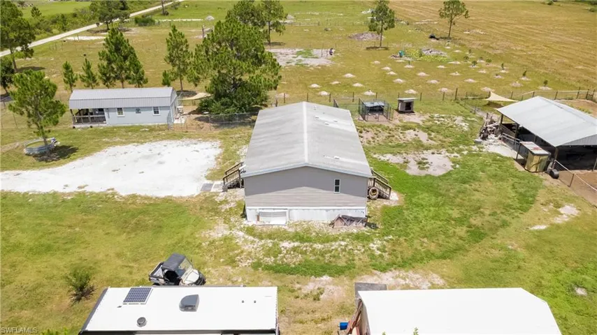 Spacious property featuring multiple structures including a central building with a light gray exterior and a secondary building with a covered porch