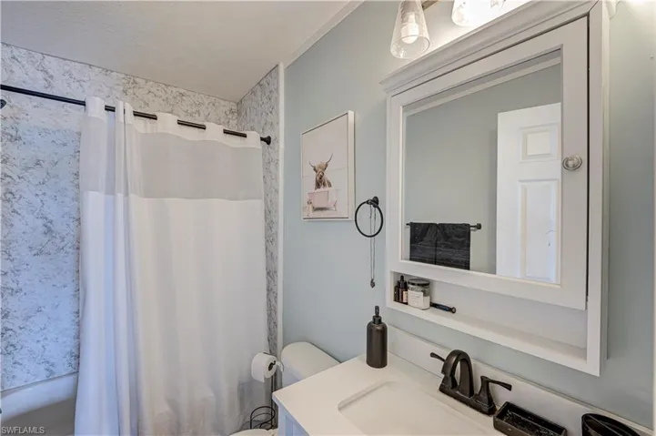 Bathroom featuring a built-in white vanity with integrated sink, matte black faucet, and a framed mirror with integrated storage