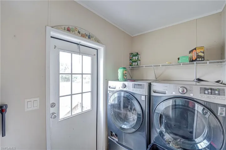 Utility area featuring a glass-paned exterior door, overhead shelving, and wall paneling