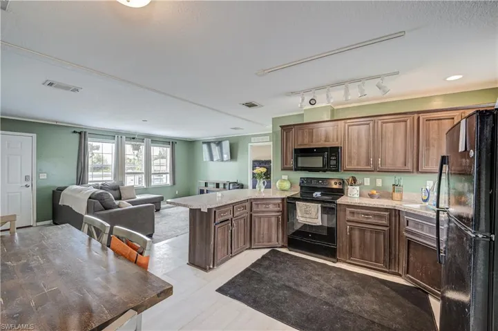 Kitchen featuring wood-finish cabinetry, light-toned countertops, and black appliances