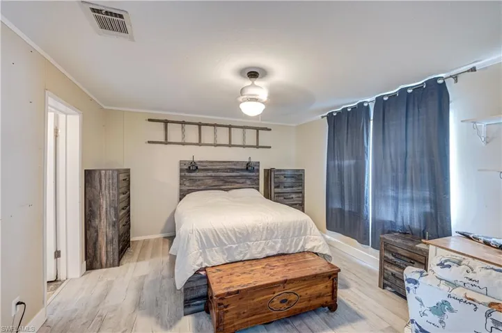 Interior room featuring wood-finish flooring, light-toned walls, and crown molding