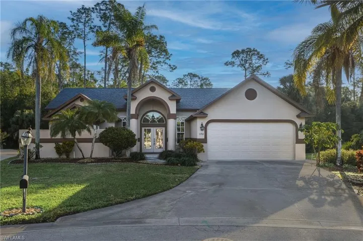 View of front of home featuring french doors, stucco siding, a front lawn, concrete driveway, and a garage