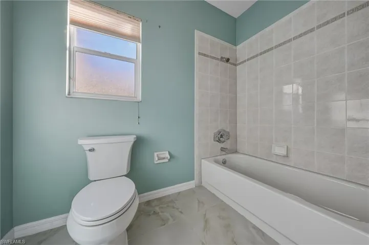 Full bathroom featuring marble finish flooring and shower / tub combination