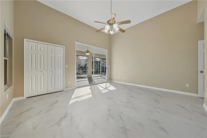 Unfurnished bedroom with access to exterior, ceiling fan, a closet, light marble finish flooring, and vaulted ceiling
