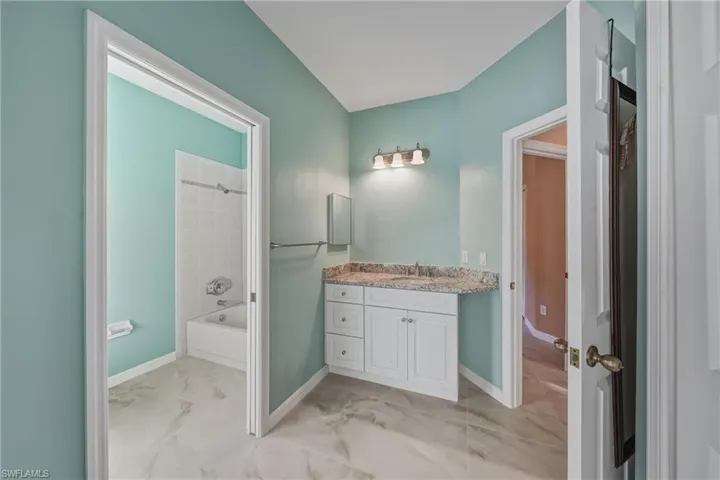 Full bathroom with light marble finish floors, shower / tub combination, and vanity