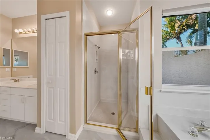 Full bathroom featuring a closet, a shower stall, vanity, and a bath