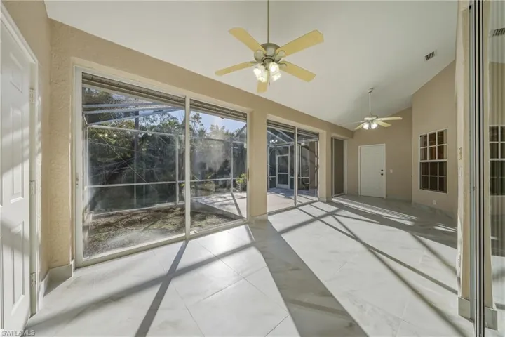 Unfurnished sunroom with a ceiling fan, lofted ceiling, and a patio