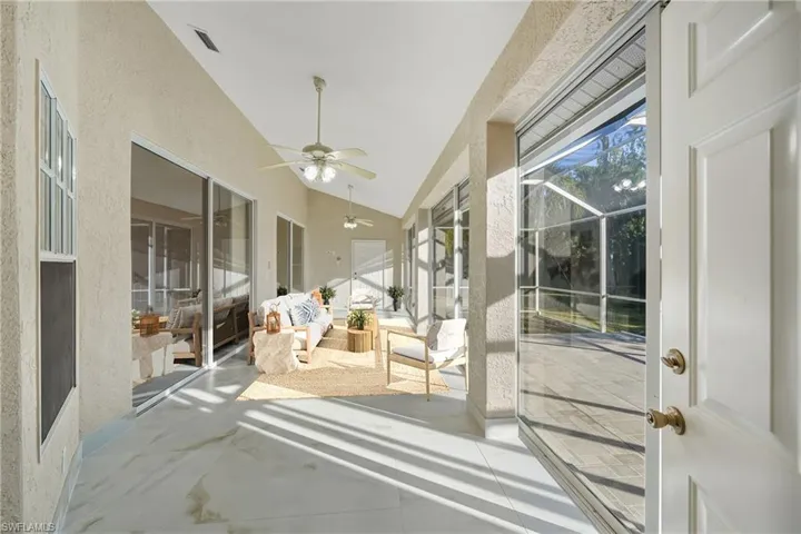 Sunroom / solarium with ceiling fan, vaulted ceiling, and a patio