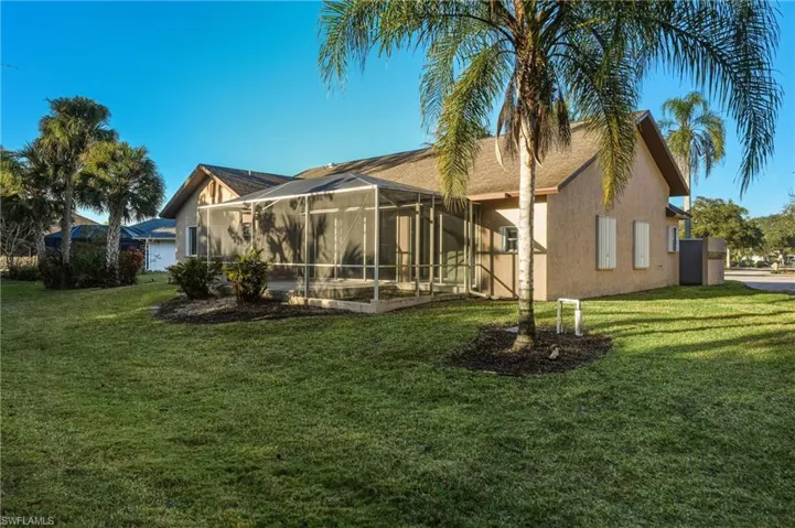 Back of house with a sunroom, stucco siding, glass enclosure, and a yard