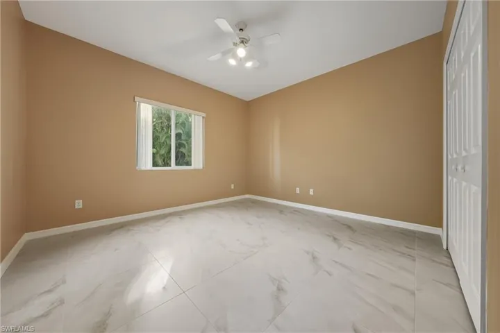 Unfurnished bedroom with a closet, ceiling fan, and light marble finish flooring