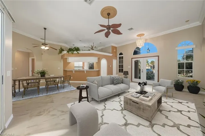 Living room featuring french doors, arched walkways, crown molding, ceiling fan, and hanging lights