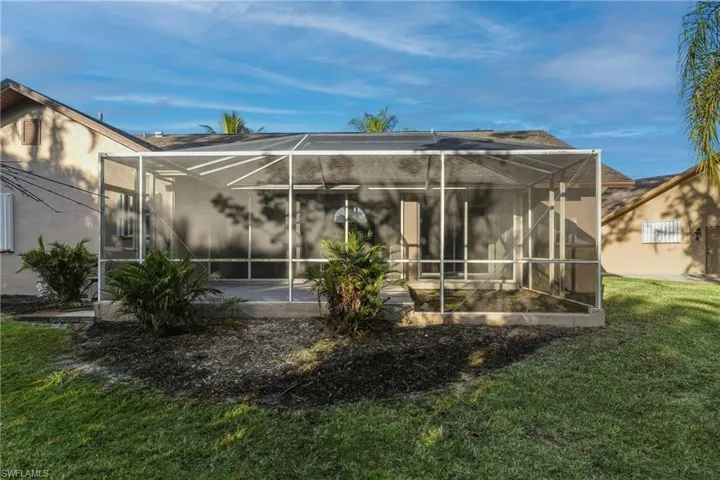 Back of property with glass enclosure, a sunroom, and a yard