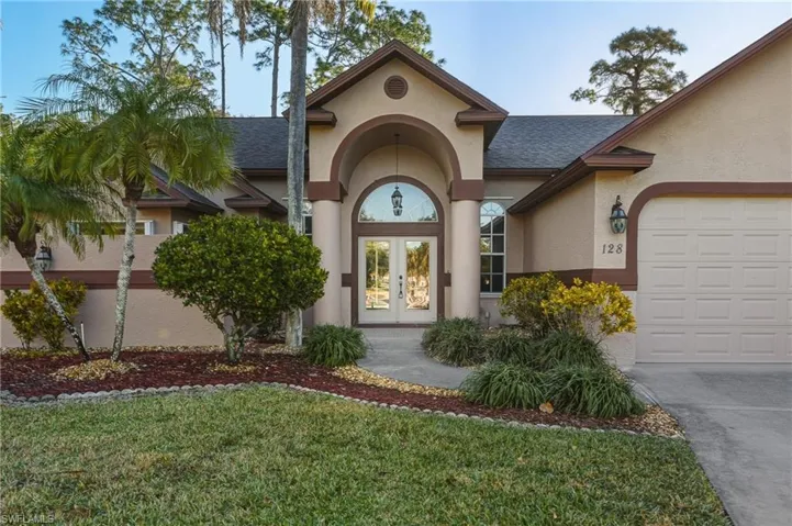 Entrance to property with french doors, a shingled roof, stucco siding, a yard, and driveway