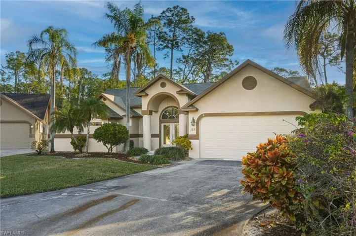 View of front of house featuring stucco siding, driveway, a garage, and a front lawn