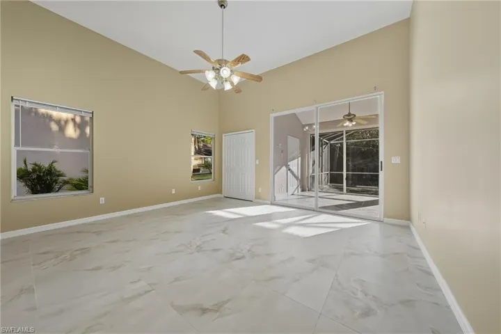 Unfurnished room featuring light marble finish floors, a ceiling fan, and lofted ceiling