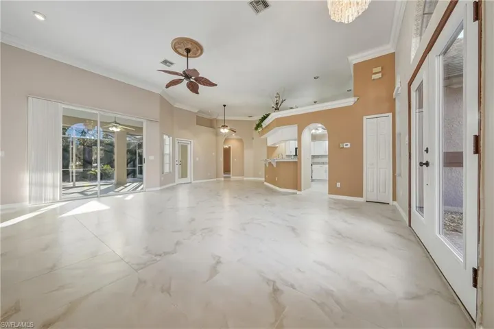 Unfurnished living room featuring ornamental molding, arched walkways, and ceiling fan