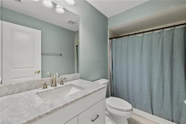 The guest bathroom is brand-new with porcelain tile, luxury vinyl flooring, white shaker cabinets, and a quartz vanity.