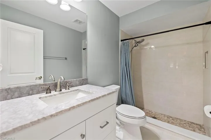 The guest bathroom is brand-new with porcelain tile, luxury vinyl flooring, white shaker cabinets, and a quartz vanity.