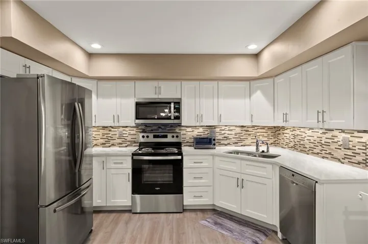 The newly remodeled kitchen features stainless steel appliances, a tasteful backsplash, white cabinetry, and luxury vinyl flooring, combining style and functionality seamlessly.